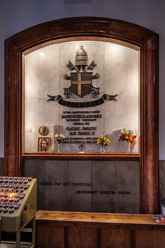 Tablica pamiątkowa poświęcona papieżowi Janowi Pawłowi II w ścianie kościoła.