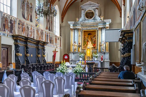 Prezbiterium świątyni z klasycystycznym ołtarzem głównym i czarnymi barokowymi stallami.