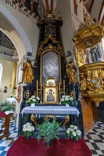 Czarny barokowy ołtarz boczny z obrazem Matki Boskiej obok złoconej ambony w bazylice św. Jakuba.