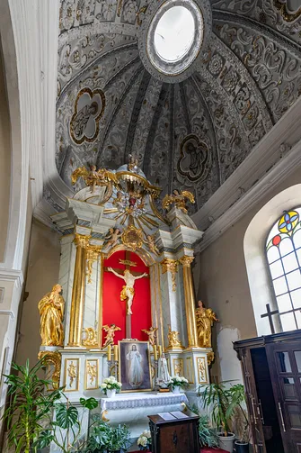 Ołtarz boczny z Ukrzyżowaniem pod bogato sztukowaną kopułą kaplicy w piotrkowskim kościele.
