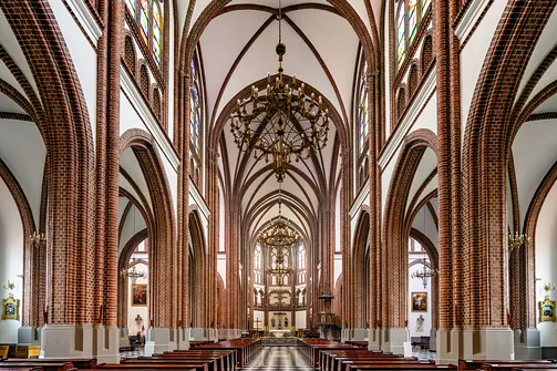 Monumentalne wnętrze bazyliki katedralnej św. Michała i św. Floriana w Warszawie z widokiem na nawę główną.