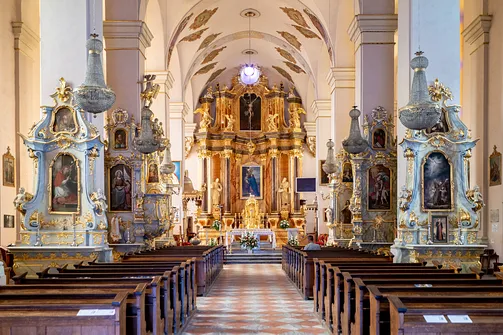 Nawa główna bazyliki kolegiackiej w Sejnach z rzędami ław i bogato zdobionym ołtarzem głównym.