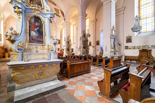 Barokowy ołtarz boczny oraz rzędy drewnianych ław w nawie głównej sejneńskiej bazyliki.
