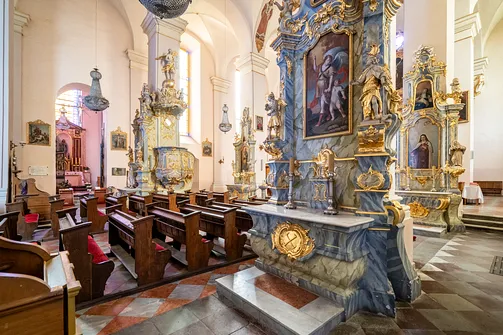 Zabytkowe ławy kościelne i marmoryzowane ołtarze boczne w bazylice Nawiedzenia NMP w Sejnach.