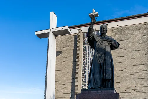 Pomnik papieża Jana Pawła II na tle monumentalnej ściany frontowej bazyliki w Stalowej Woli.