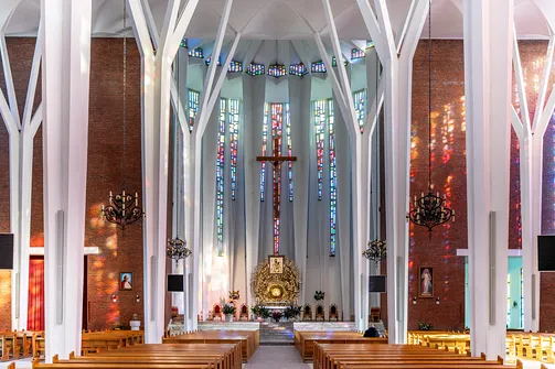 Widok na prezbiterium bazyliki w Stalowej Woli z wielobarwnymi witrażami oświetlającymi wnętrze.