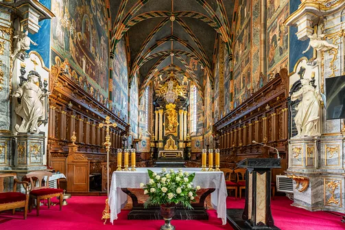Widok na prezbiterium bazyliki w Sandomierzu z ołtarzem posoborowym i ścianami pokrytymi polichromią.