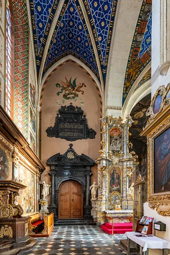 Portal wejściowy i barokowy ołtarz boczny pod ozdobnym sklepieniem bazyliki w Sandomierzu.
