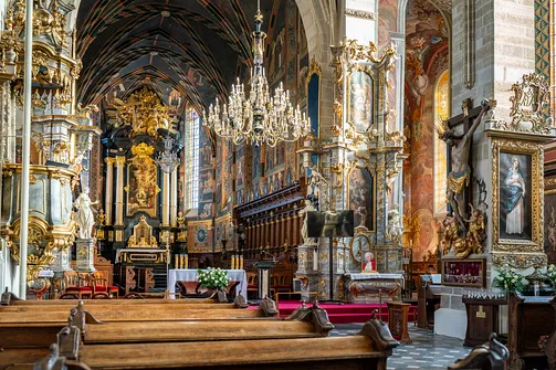 Widok przez ławki na ołtarz główny i monumentalny krucyfiks w katedrze w Sandomierzu.
