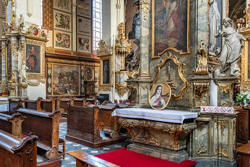 Drewniane ławy i barokowy ołtarz boczny w katedrze w Sandomierzu.