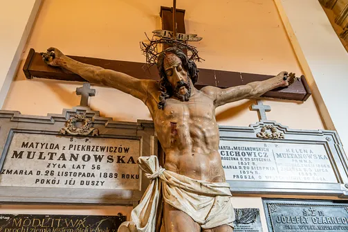Drewniany krucyfiks z figurą Jezusa Chrystusa oraz marmurowe tablice epitafijne w kruchcie warszawskiej świątyni.
