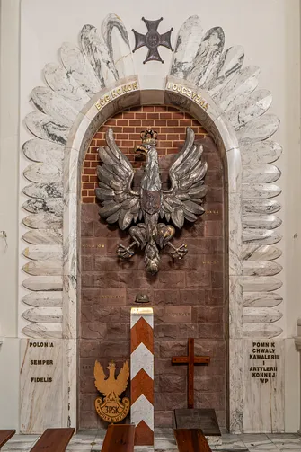 Srebrny orzeł państwowy oraz symbole wojskowe w kompozycji ołtarza Ojczyzny w bocznej kaplicy świątyni.