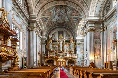 Nawa główna warszawskiej świątyni z widokiem na chór muzyczny i rokokowy prospekt organowy.