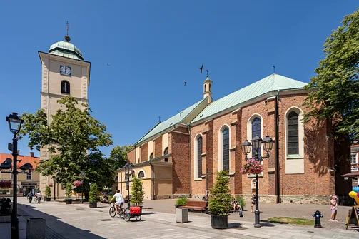 Widok na kościół św. Wojciecha i Stanisława w Rzeszowie wraz z dzwonnicą i otaczającym go placem.