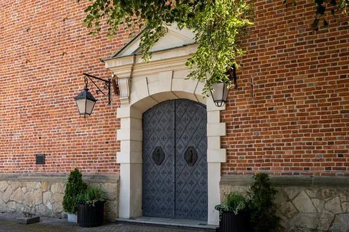 Kamienny, barokowy portal wejściowy z ozdobnymi drzwiami prowadzącymi do wnętrza rzeszowskiej fary.