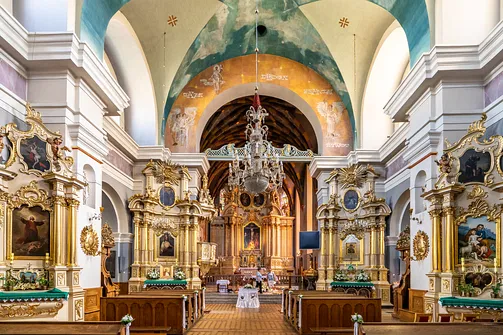 Wnętrze kościoła św. Wojciecha i Stanisława w Rzeszowie z widocznym żyrandolem i polichromią ścienną.