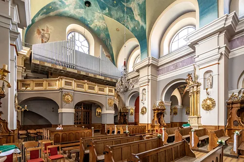 Wnętrze rzeszowskiej fary z widokiem na drewniane ławki dla wiernych oraz emporę organową.