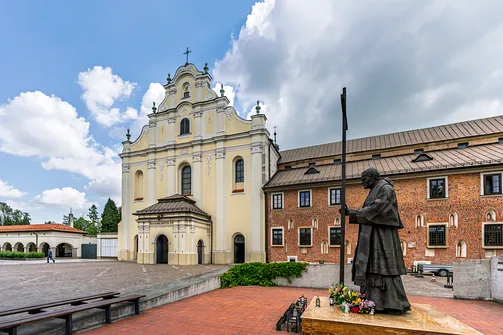 Barokowa fasada kościoła oo. Cystersów w Mogile oraz pomnik Jana Pawła II na dziedzińcu przedświątynnym.