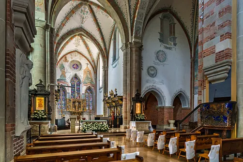 Wnętrze kościoła oo. Cystersów ukazujące połączenie surowego kamienia z bogactwem barokowych ołtarzy.
