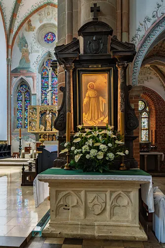Barokowy ołtarz boczny z obrazem świętego, usytuowany przy kamiennym filarze w mogilskiej bazylice.