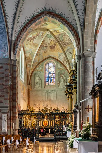 Widok na Kaplicę Cudownego Krzyża Mogilskiego z perspektywy nawy głównej przez ozdobną kratę.