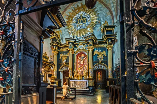 Wnętrze Kaplicy Cudownego Krzyża widziane przez kratę wejściową na tle ołtarza.