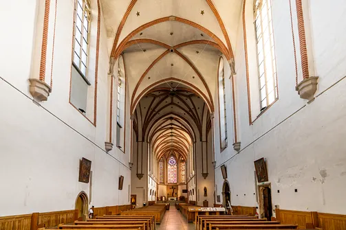 Wnętrze kościoła św. Wojciecha we Wrocławiu – widok przez nawę główną w stronę prezbiterium i witraży.