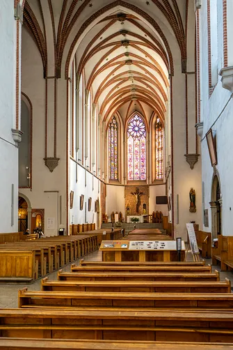 Nawa główna kościoła św. Wojciecha we Wrocławiu z drewnianymi ławkami i strzelistym sklepieniem gotyckim.