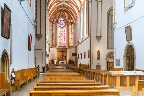 Gotyckie wnętrze kościoła św. Wojciecha we Wrocławiu – widok na rzędy ławek, prezbiterium oraz boczne portale.
