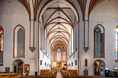 Perspektywa nawy głównej kościoła św. Wojciecha we Wrocławiu, podkreślająca rytm gotyckich filarów i łuków.