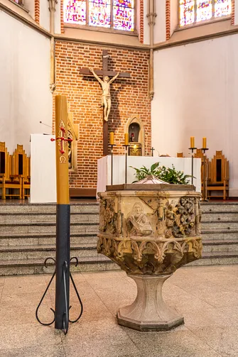 Zabytkowa, kamienna chrzcielnica z płaskorzeźbami w kościele św. Wojciecha we Wrocławiu obok paschału.