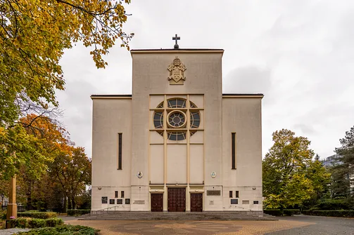 Symetryczna fasada warszawskiej konkatedry Matki Bożej Zwycięskiej z centralną rozetą i papieskim herbcem.