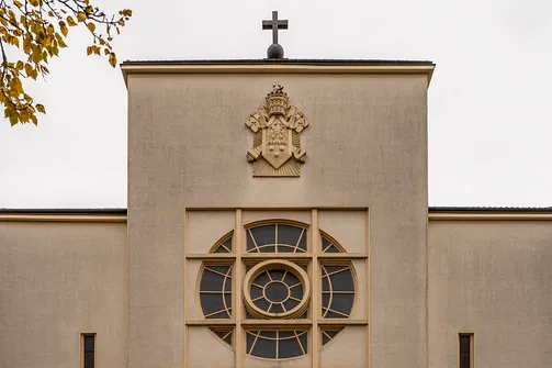 Detal architektoniczny fasady konkatedry Matki Bożej Zwycięskiej w Warszawie z godłem oraz geometryczną rozetą.