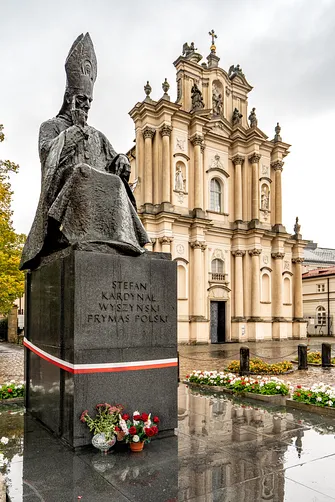 Pomnik Stefana Kardynała Wyszyńskiego Prymasa Polski na tle fasady Kościoła Wizytek w Warszawie.