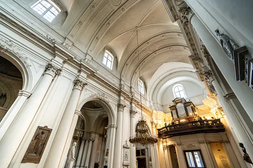 Perspektywa jasnego korpusu nawowego z emporą organową w głębi warszawskiej świątyni.