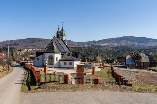Widok na bryłę kościoła parafialnego w Hucisku od strony prezbiterium na tle panoramy Beskidów.