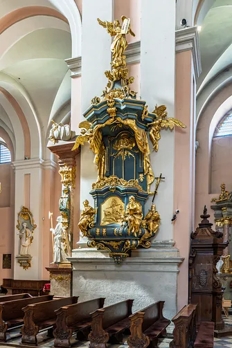 Rokokowa ambona ze złoconymi rzeźbami i zwieńczeniem przy filarze w nawie głównej.