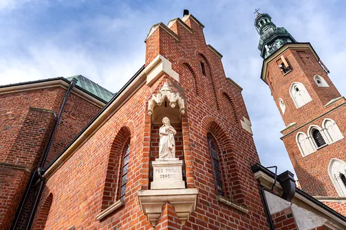 Figury w niszach elewacji kościoła farnego w Radomiu na tle gotyckiej wieży.