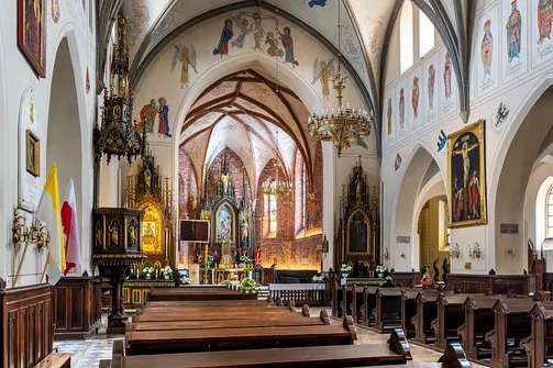 Wnętrze radomskiej fary z widokiem na ambonę, ołtarze boczne oraz prezbiterium.