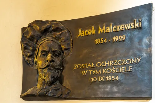 Tablica z płaskorzeźbą upamiętniająca chrzest Jacka Malczewskiego.