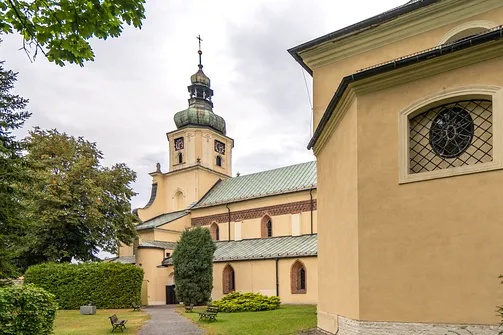 Południowa elewacja nawy bocznej kościoła w Rudach z widocznymi ostrołukowymi oknami i wieżą.