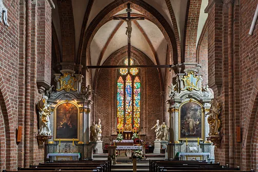 Przestrzeń prezbiterium rudzkiej świątyni z ołtarzem głównym i bocznymi strukturami retabulów.