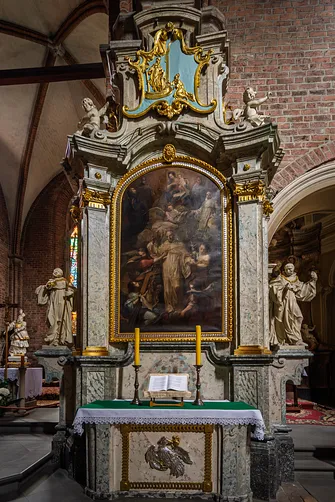 Barokowy ołtarz boczny ze złoceniami i figurami świętych przy filarze rudzkiej świątyni.