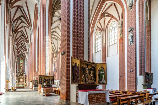 Nawa boczna gotyckiej świątyni na Piasku z widocznym sklepieniem i ołtarzem.