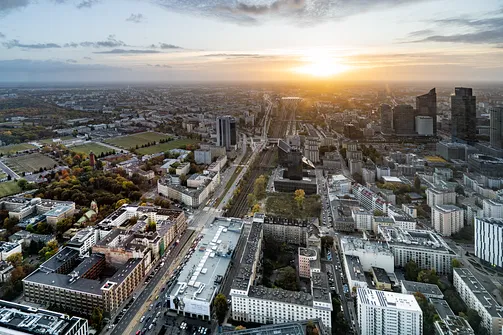 Zachód słońca nad linią kolejową i osią alei Jerozolimskich w widoku z góry wieżowca Varso Tower.