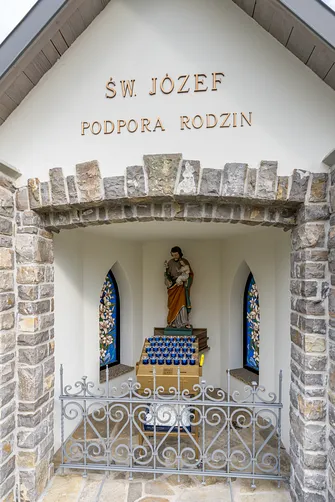 Wnętrze kamiennej kapliczki z figurą św. Józefa w otoczeniu ogrodzenia sanktuarium w Hałcnowie.