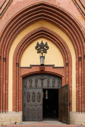 Ostrołukowy portal wejściowy z reliefowymi drzwiami bazyliki św. Antoniego w Rybniku.