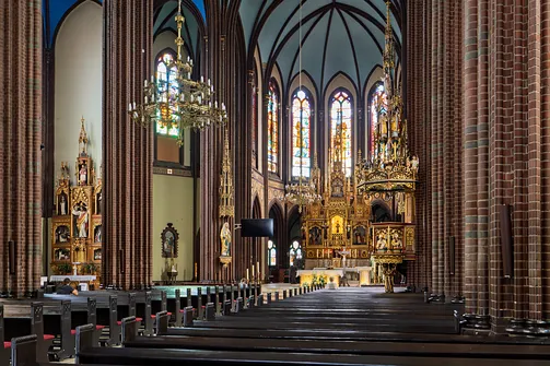 Wnętrze nawy głównej rybnickiej bazyliki z widokiem na ambonę i neogotycki ołtarz.