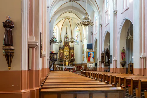 Widok na prezbiterium kościoła w Rędzinach z widoczną amboną po lewej stronie i rzędami ław