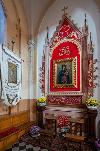 Obraz Matki Bożej Nieustającej Pomocy z wotami w bocznej części kościoła.